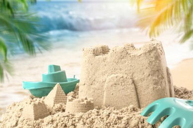 Sand castle with toys on ocean beach, closeup. Outdoor play