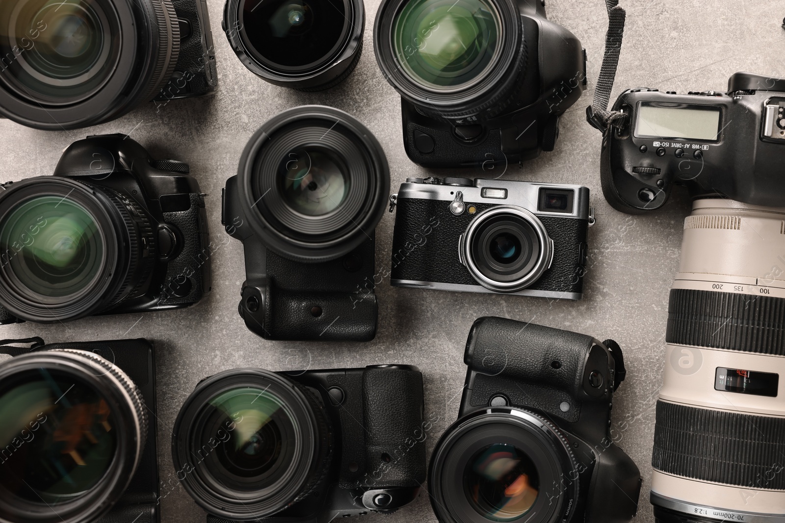 Photo of Modern cameras on gray textured table, flat lay