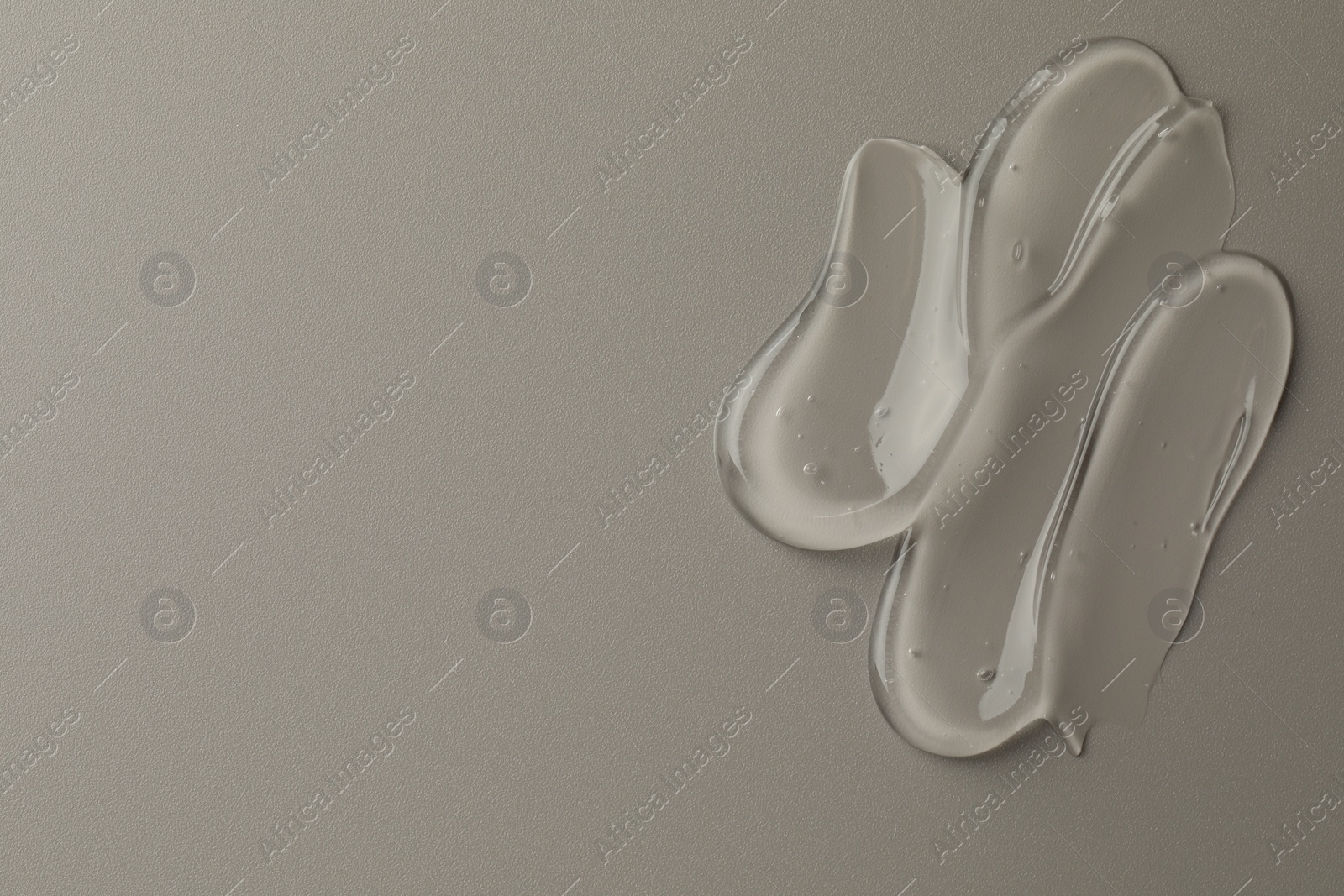 Photo of Sample of clear cosmetic gel on grey background, top view. Space for text
