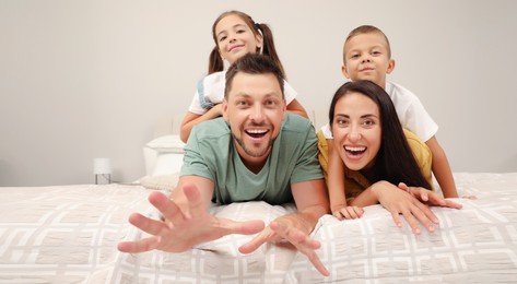 Image of Portrait of happy family with children on bed at home