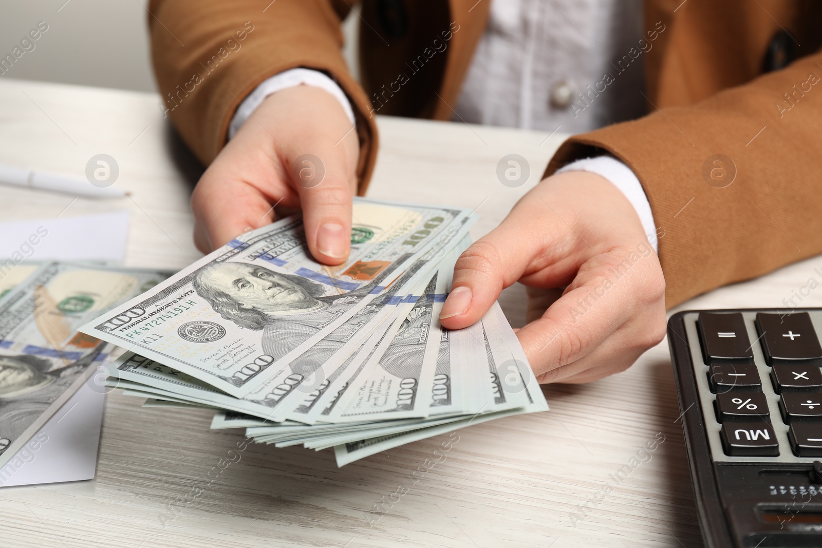 Photo of Money exchange. Woman holding dollar banknotes at white wooden table, closeup