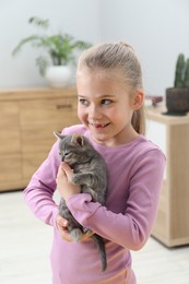 Photo of Little girl with cute fluffy kitten indoors