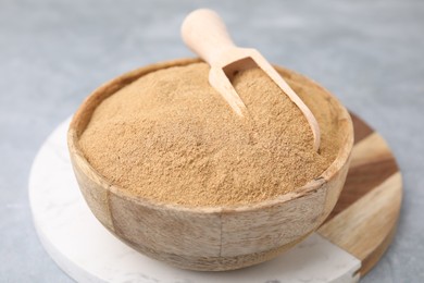 Photo of Dietary fiber. Psyllium husk powder in bowl and scoop on grey table, closeup