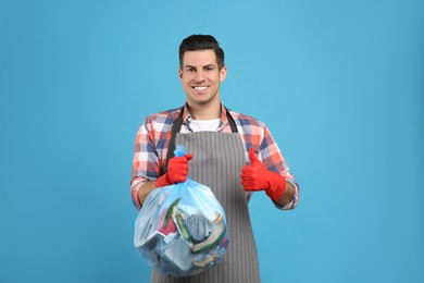 Photo of Man holding full garbage bag on light blue background
