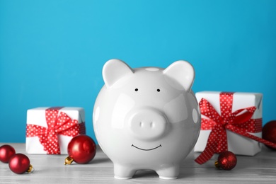 Cute piggy bank with Christmas balls and gifts on table