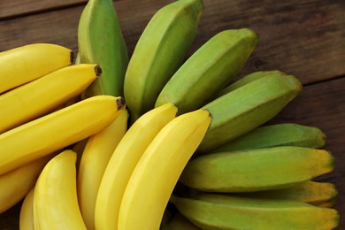 Photo of Bunches of tasty bananas on wooden table, closeup