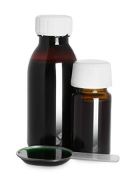 Photo of Bottles of cough syrup and dosing spoon on white background