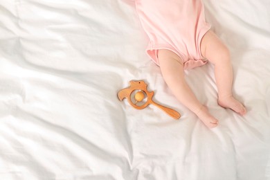 Photo of Cute baby and rattle toy on sheets, top view. Space for text