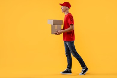 Happy courier with parcels on yellow background. Space for text