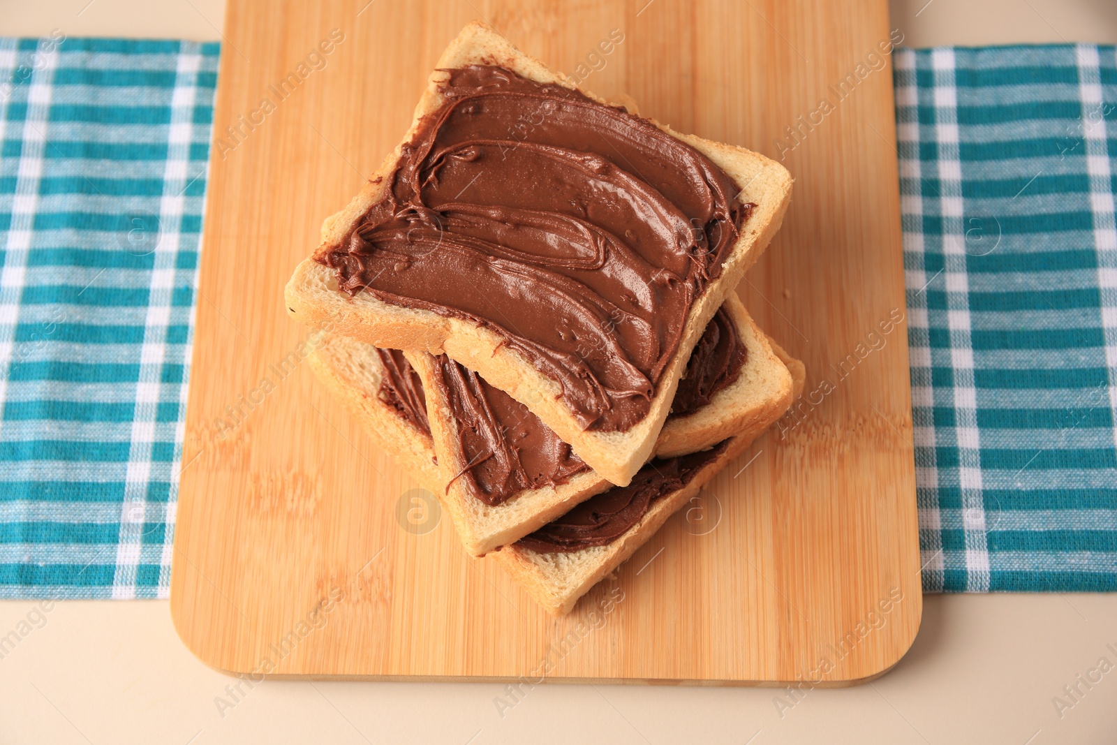 Photo of Tasty toasts with chocolate paste on beige table