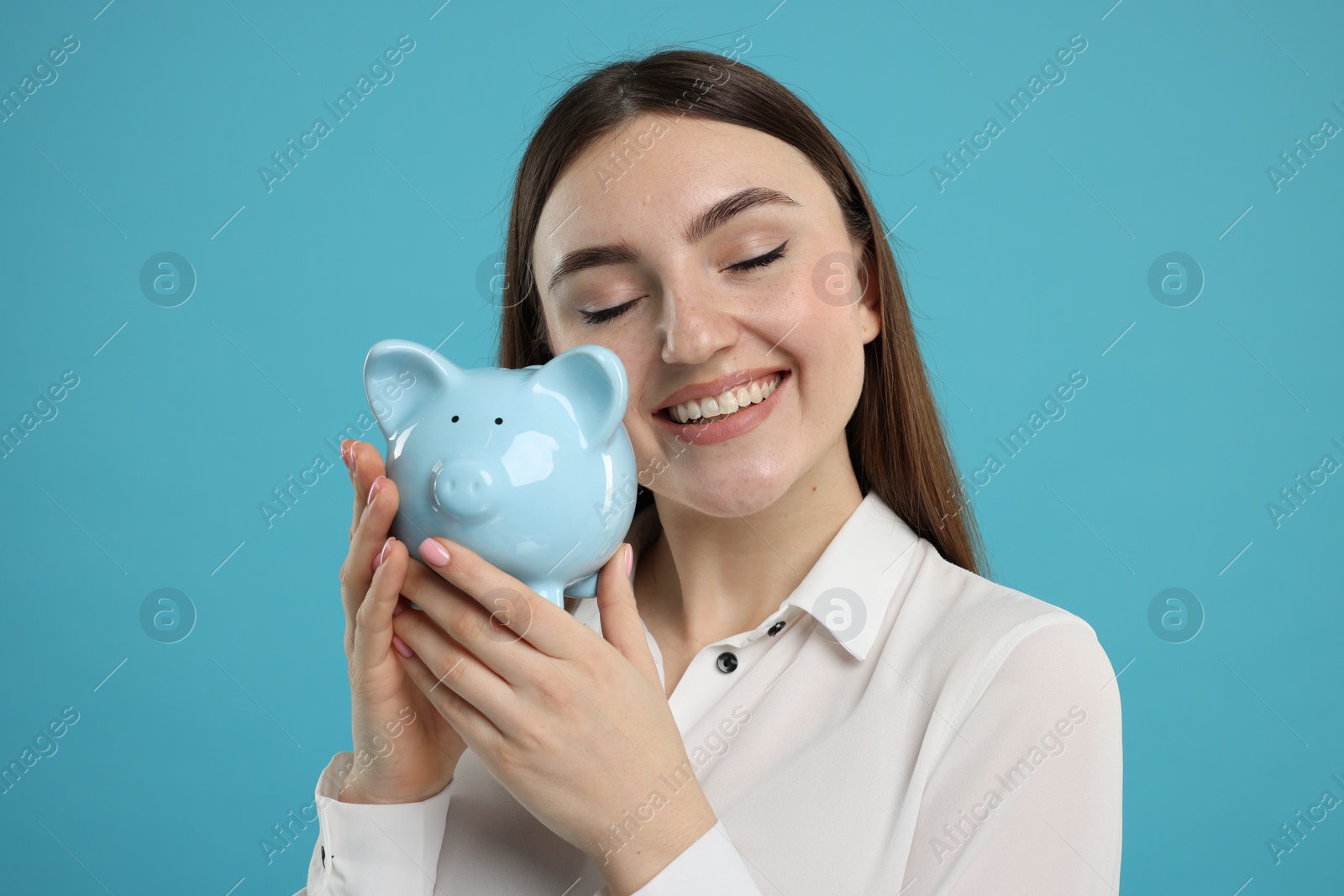 Photo of Happy woman with piggy bank on light blue background