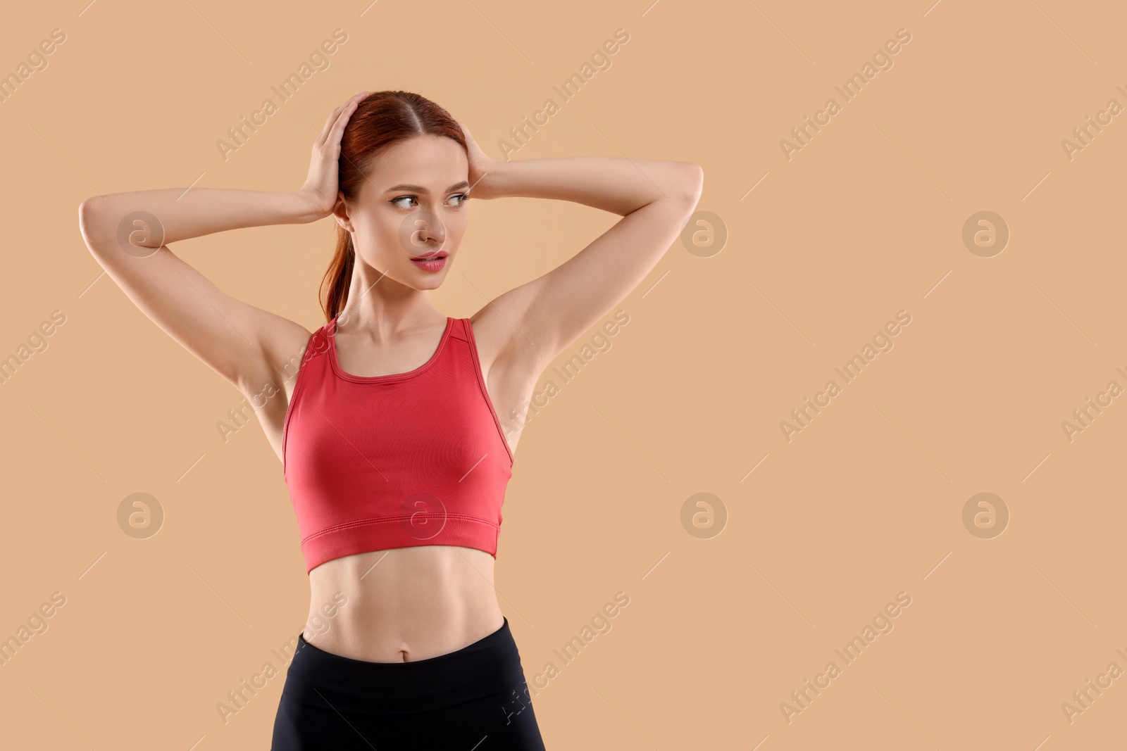 Photo of Young woman in sportswear on beige background, space for text