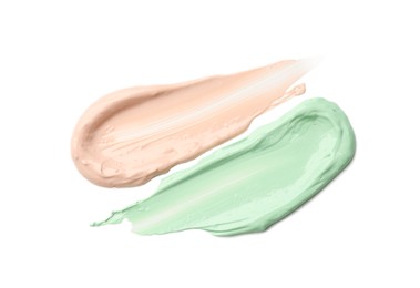 Strokes of pink and green color correcting concealers isolated on white, top view