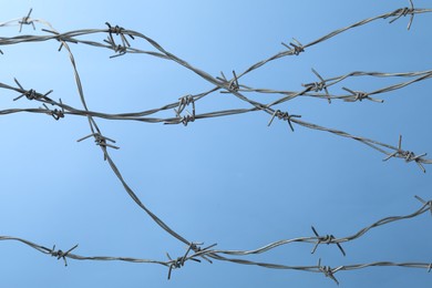 Metal barbed wire on light blue background