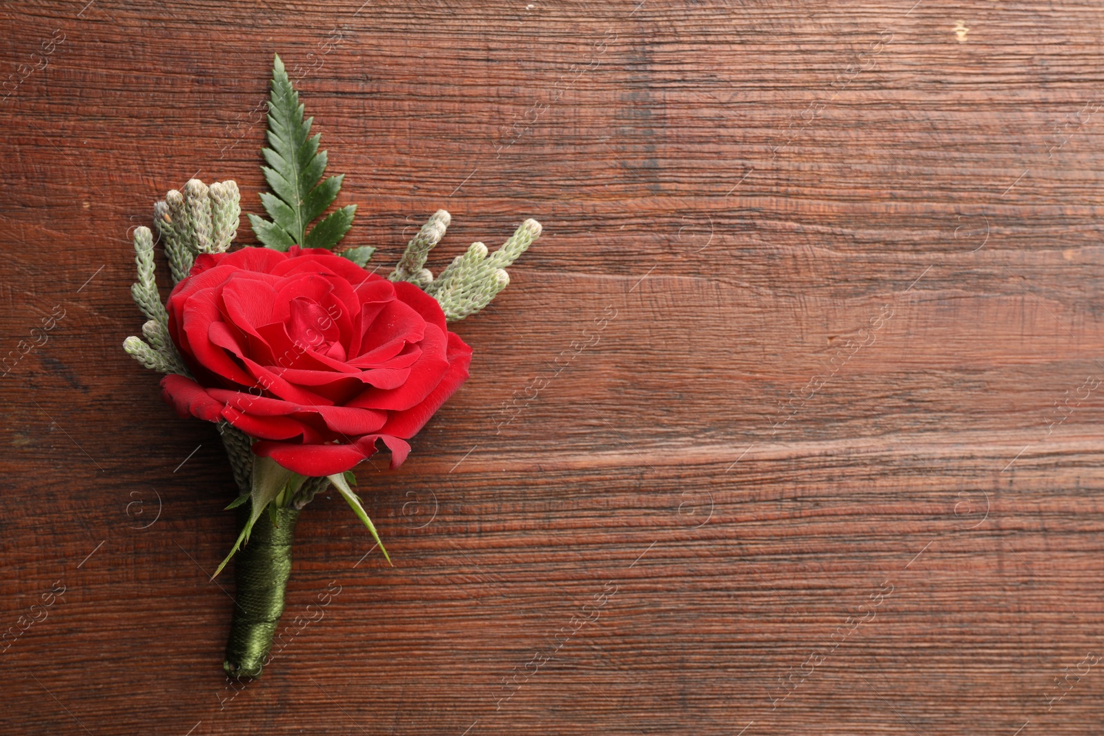 Photo of One stylish red boutonniere on wooden table, top view. Space for text
