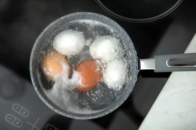 Photo of Boiling chicken eggs in saucepan on electric stove, top view