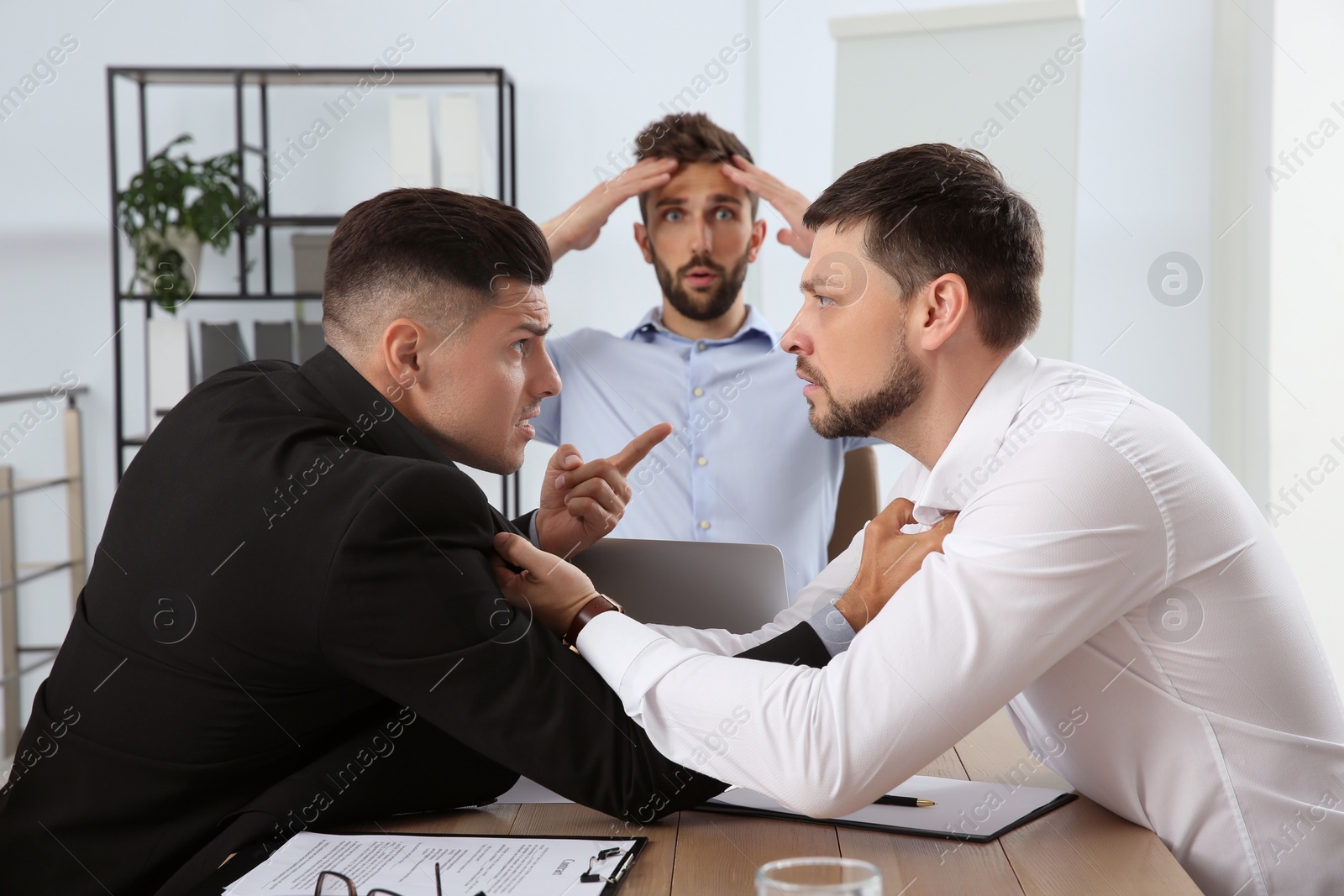 Photo of Emotional colleagues fighting in office. Workplace conflict