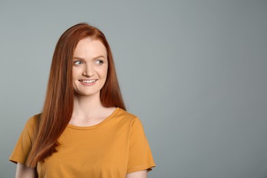 Photo of Candid portrait of happy young woman with charming smile and gorgeous red hair on grey background, space for text