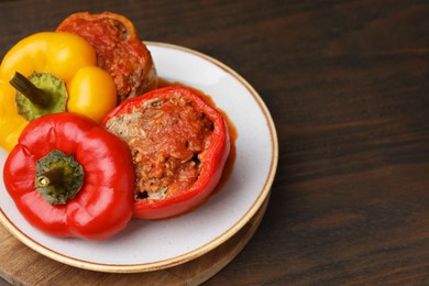 Photo of Delicious stuffed bell peppers served on wooden table. Space for text