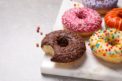 Yummy donuts with sprinkles on light grey table