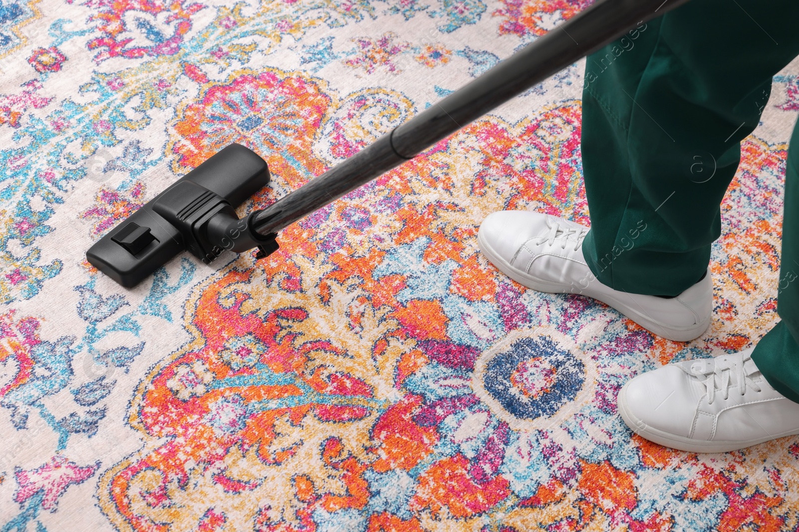 Photo of Dry cleaner's employee hoovering carpet with vacuum cleaner, closeup