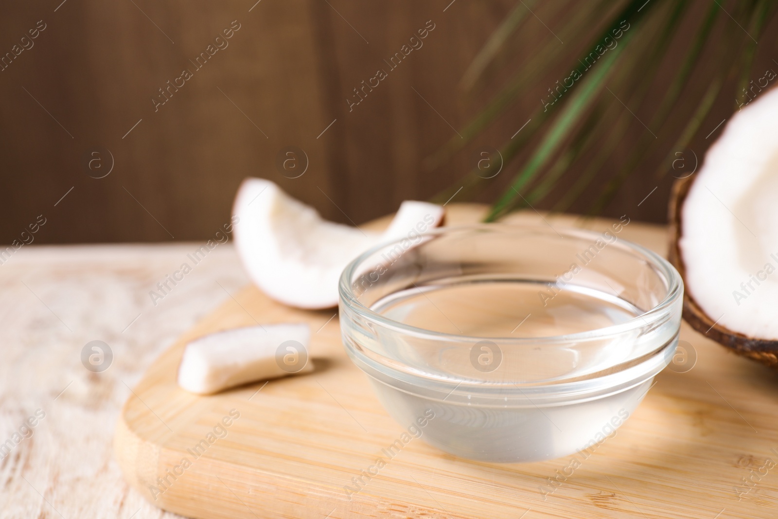 Photo of Coconut oil in glass bowl on wooden board, closeup