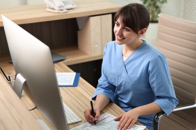 Photo of Smiling medical assistant working with documents in office