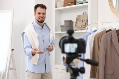 Photo of Smiling fashion blogger explaining something while recording video at home