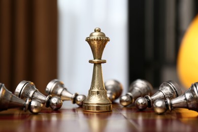 Photo of Queen piece among defeated pawns on chessboard indoors