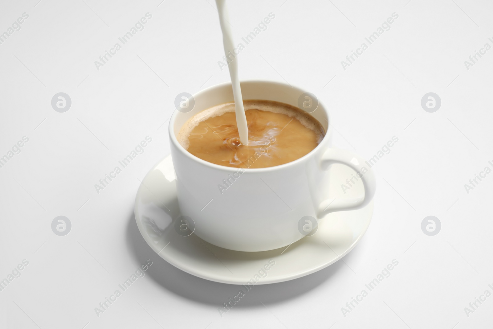 Photo of Pouring milk into cup of coffee on white background