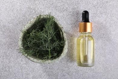 Photo of Bottle of essential oil and bowl with fresh dill on light grey table, flat lay
