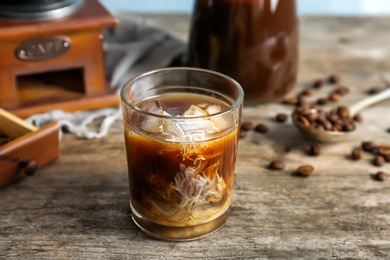 Photo of Glass with cold brew coffee and milk on wooden table