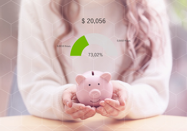 Woman with pink piggy bank at table and graph, closeup