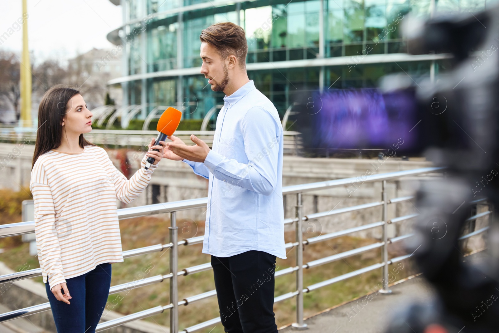 Photo of Young journalist interviewing man on city street