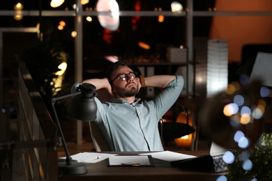 Photo of Young man working in office at night