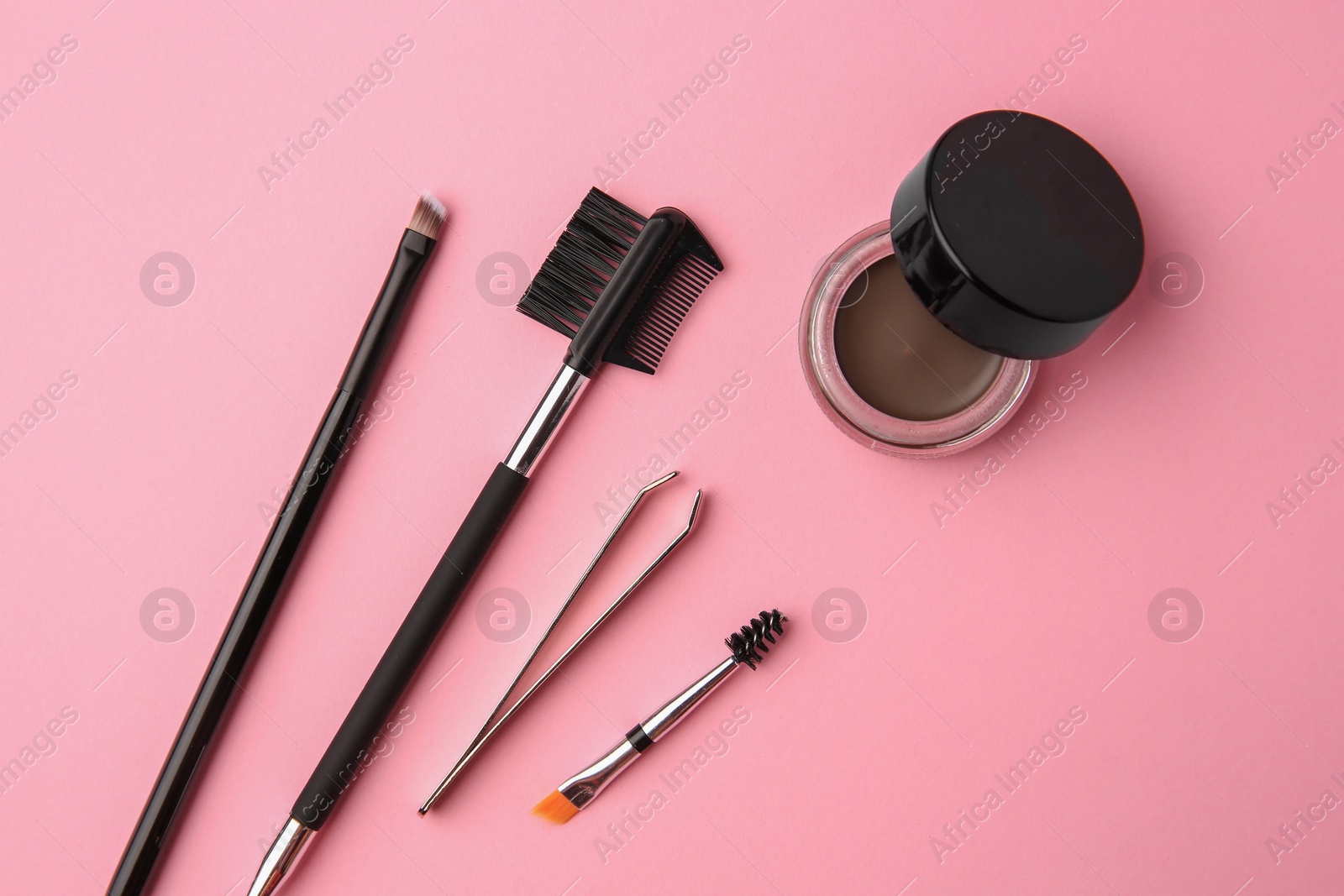 Photo of Eyebrow pomade with henna effect and professional tools on pink background, flat lay