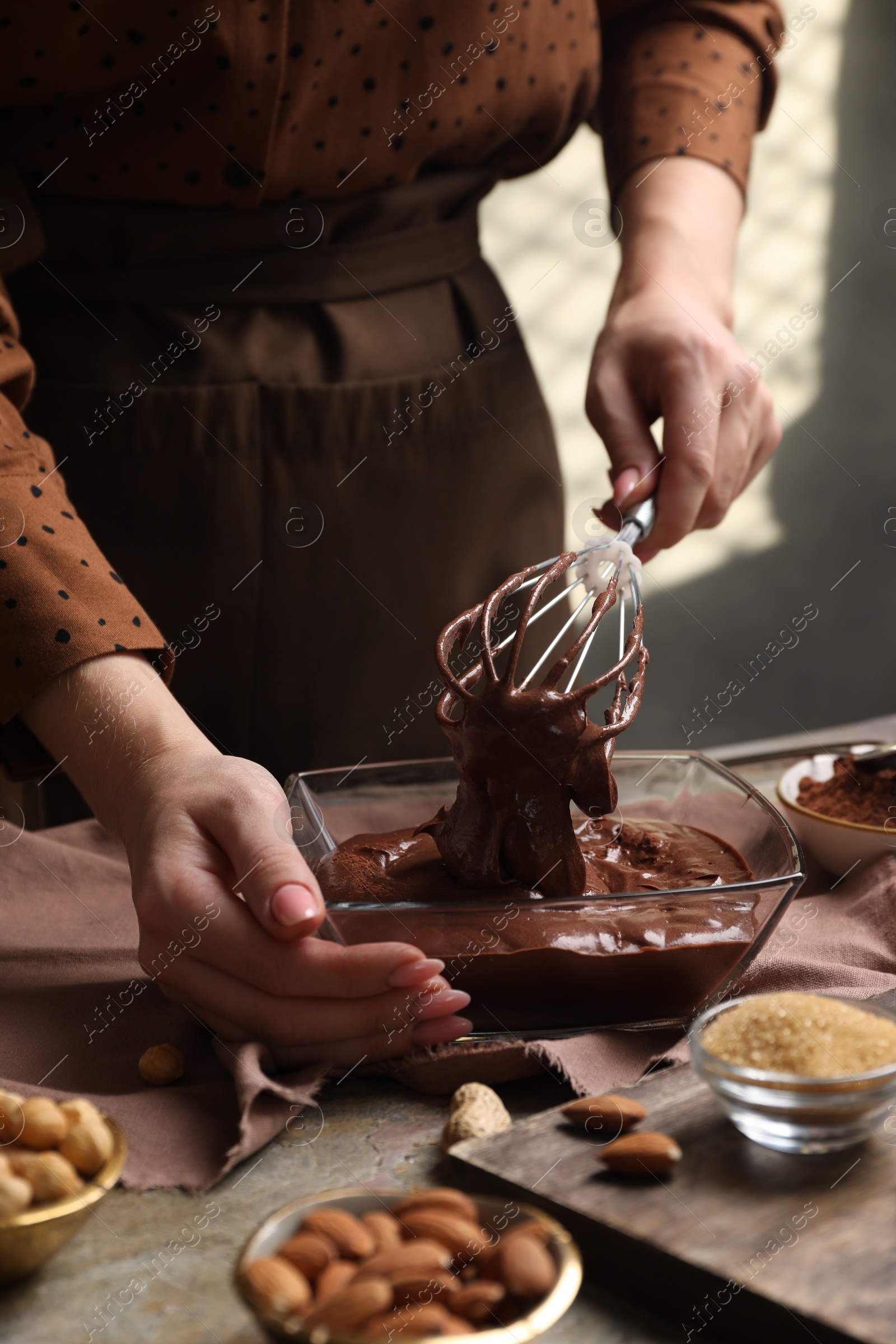 Photo of Woman mixing delicious chocolate cream with whisk at table, closeup