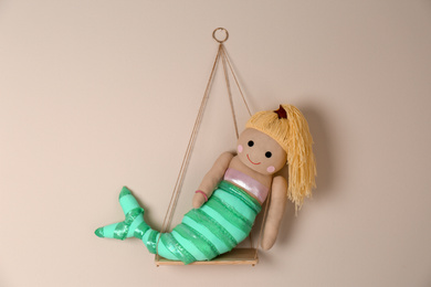 Photo of Shelf with cute toy mermaid on beige wall. Child's room interior element