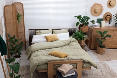 Photo of Stylish bedroom with comfortable bed and beautiful green houseplants. Interior design
