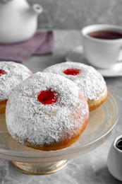 Photo of Pastry stand with delicious jelly donuts on grey table, closeup