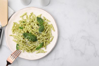 Photo of Plate of delicious trofie pasta with pesto sauce, cheese and basil leaves on white marble table, flat lay. Space for text