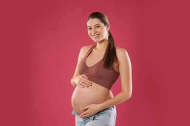 Photo of Happy young pregnant woman on red background