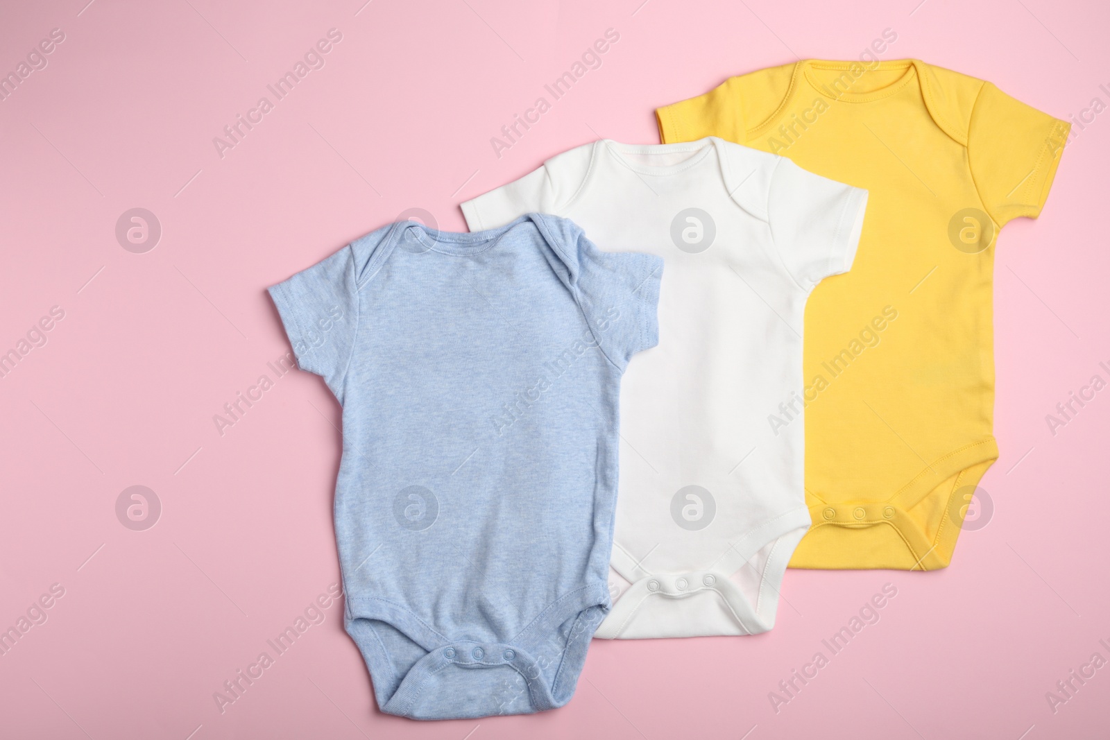 Photo of Child's bodysuits on pink background, flat lay
