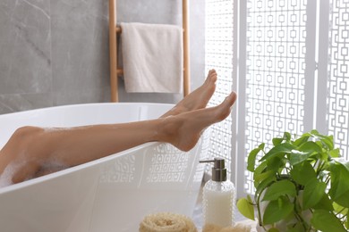 Photo of Woman taking bath and shower gel indoors, closeup