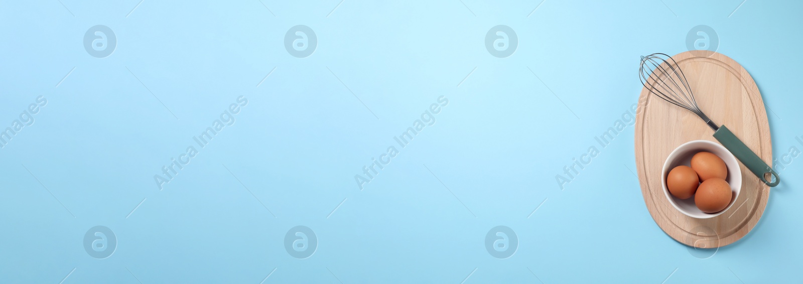 Image of Whisk and eggs on light blue background, top view. Banner design with space for text