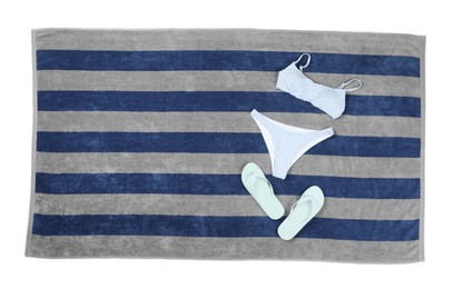 Photo of Striped beach towel with swimsuit and flip flops on white background, top view
