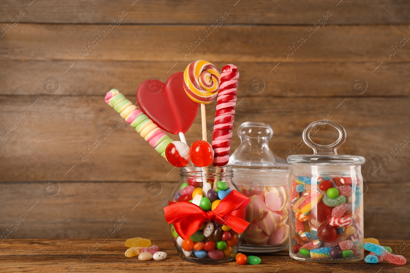 Photo of Jars with different delicious candies on wooden table