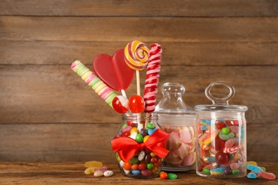Jars with different delicious candies on wooden table