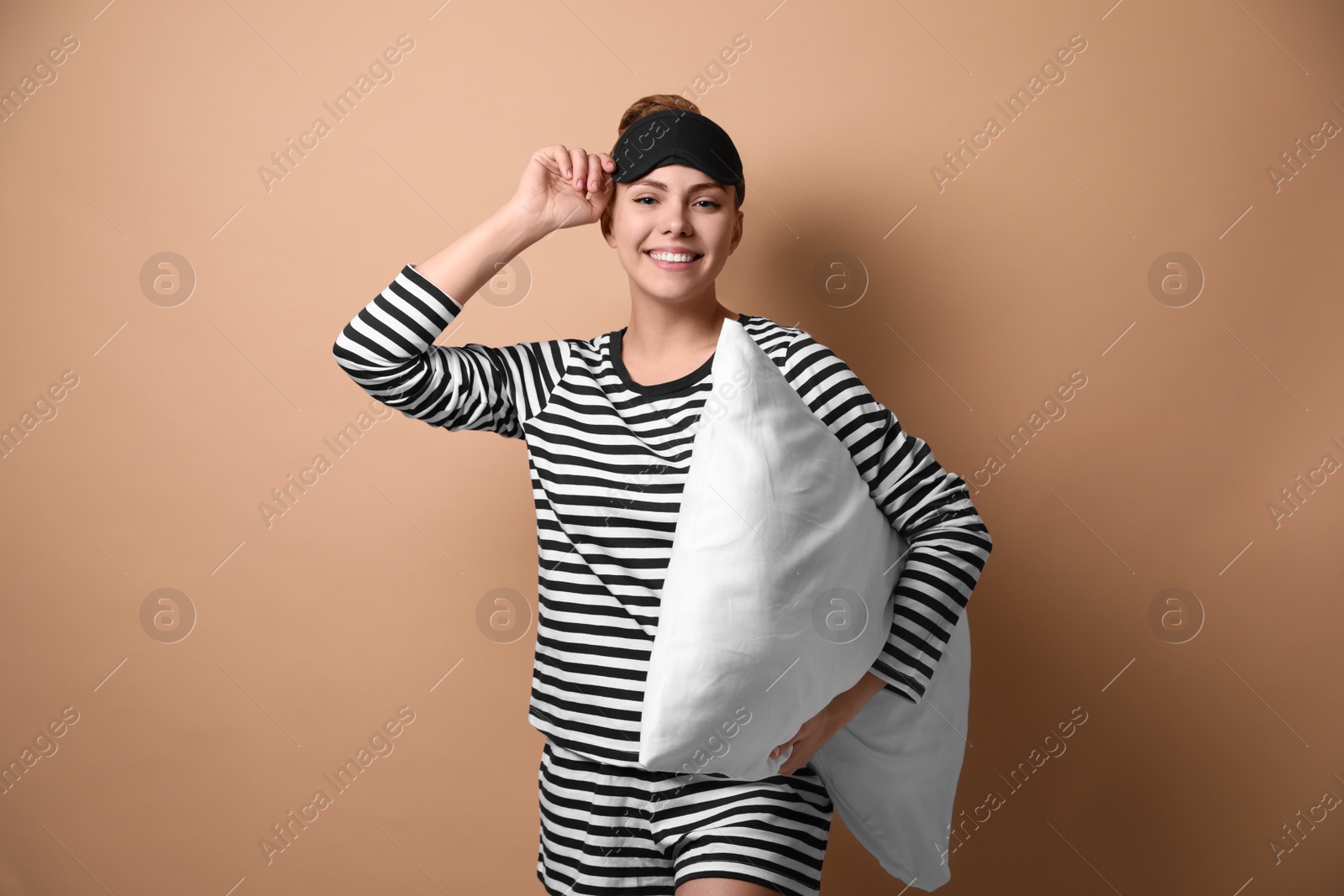 Photo of Beautiful woman with pillow on beige background. Bedtime