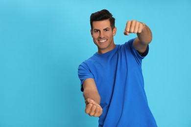 Photo of Happy man pretending to drive car on light blue background. Space for text